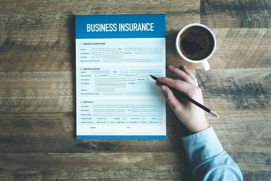 hand filling up business insurance application on table