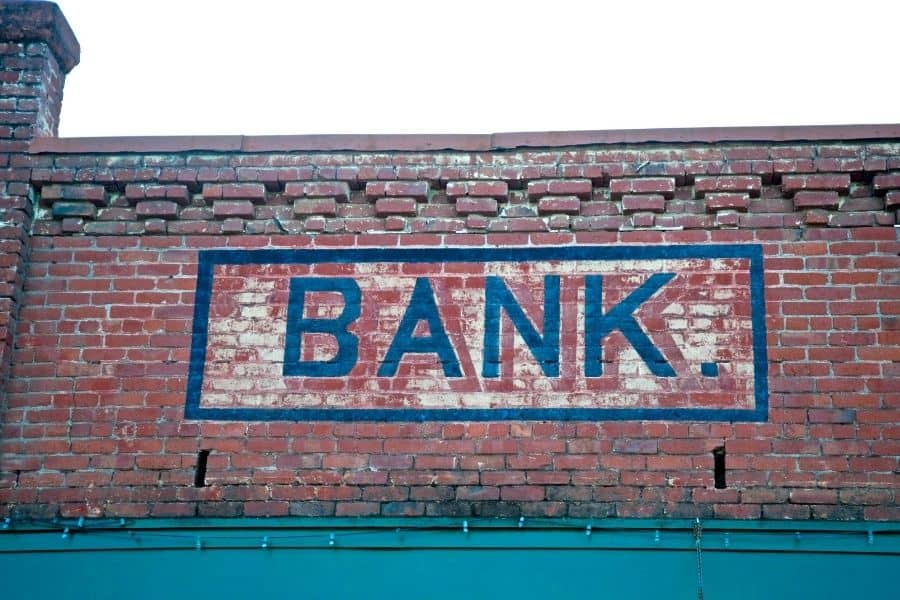 Photograph of old brick building with the words, 'Bank' painted on it.