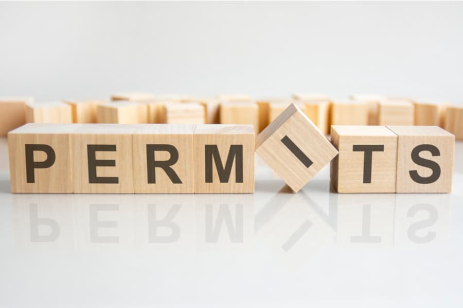 permits - word of wooden blocks with letters on a gray background. Reflection of the caption on the mirrored surface of the table. Selective focus.