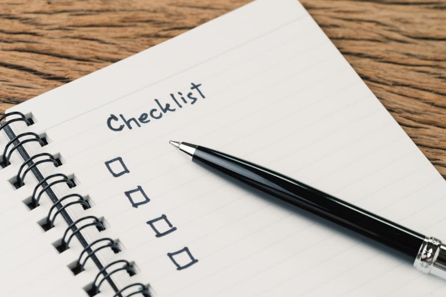 Checklist, to do list, prioritize or reminder for project plan, pen with handwriting headline the word Checklist and check box on small notepad on wood table.
