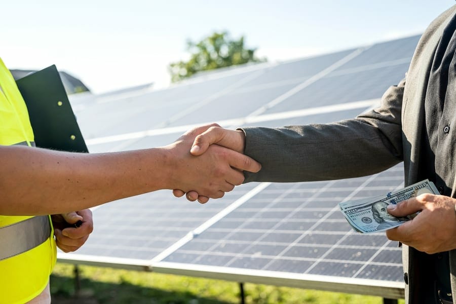 two man handshake after the conclusion of the agreement on solar panels background.