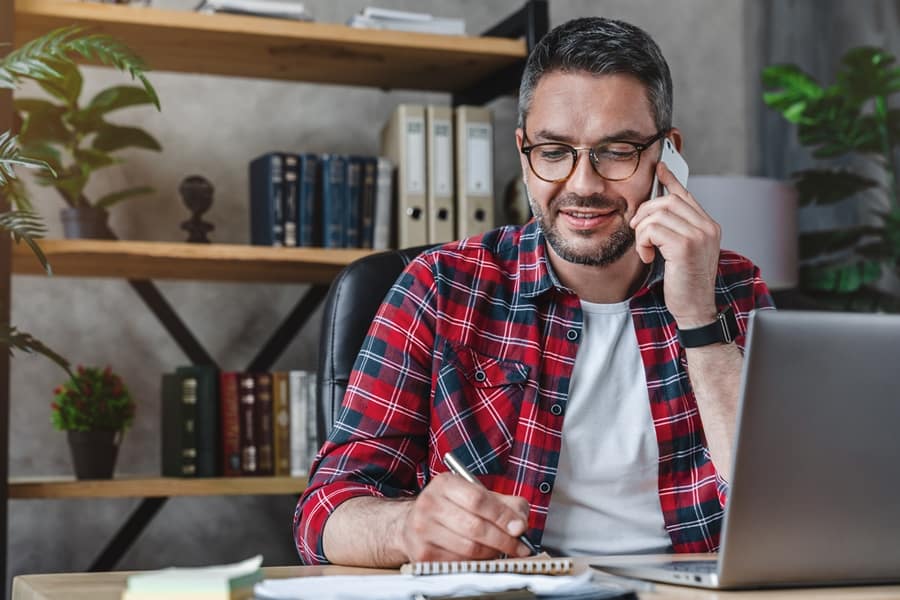businessman writing notes while making phone call