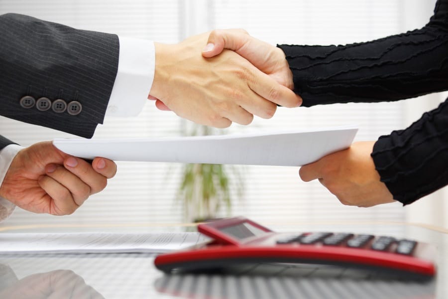 business people shaking hands while exchanging documents