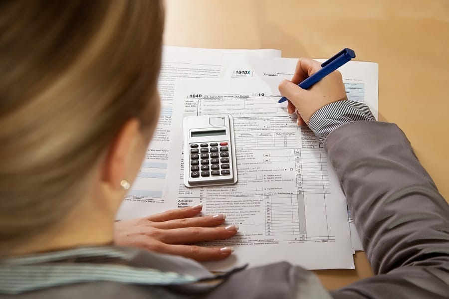 businesswoman filling income tax form with calculator