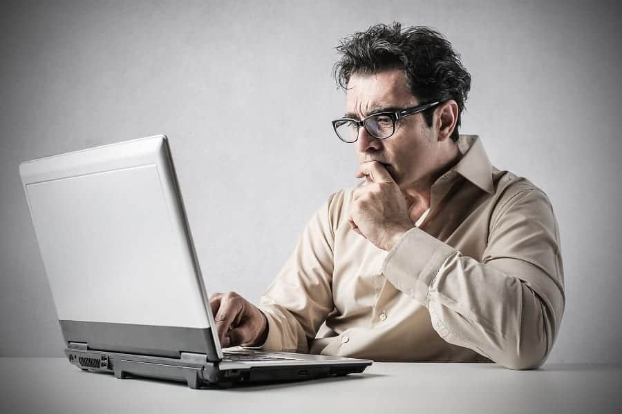 businessman weighing pros and cons using laptop business concept